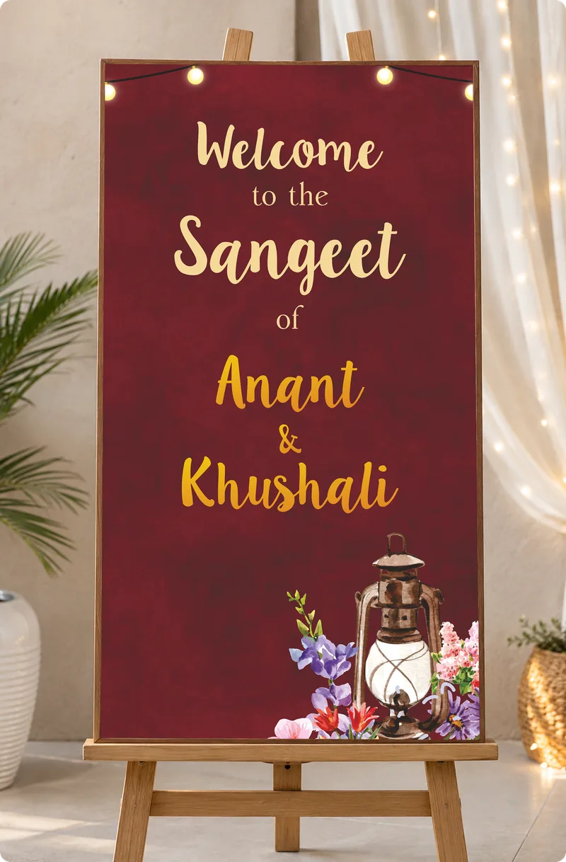 Welcome to the Sangeet of Anant & Khushali sign in maroon and gold on an easel